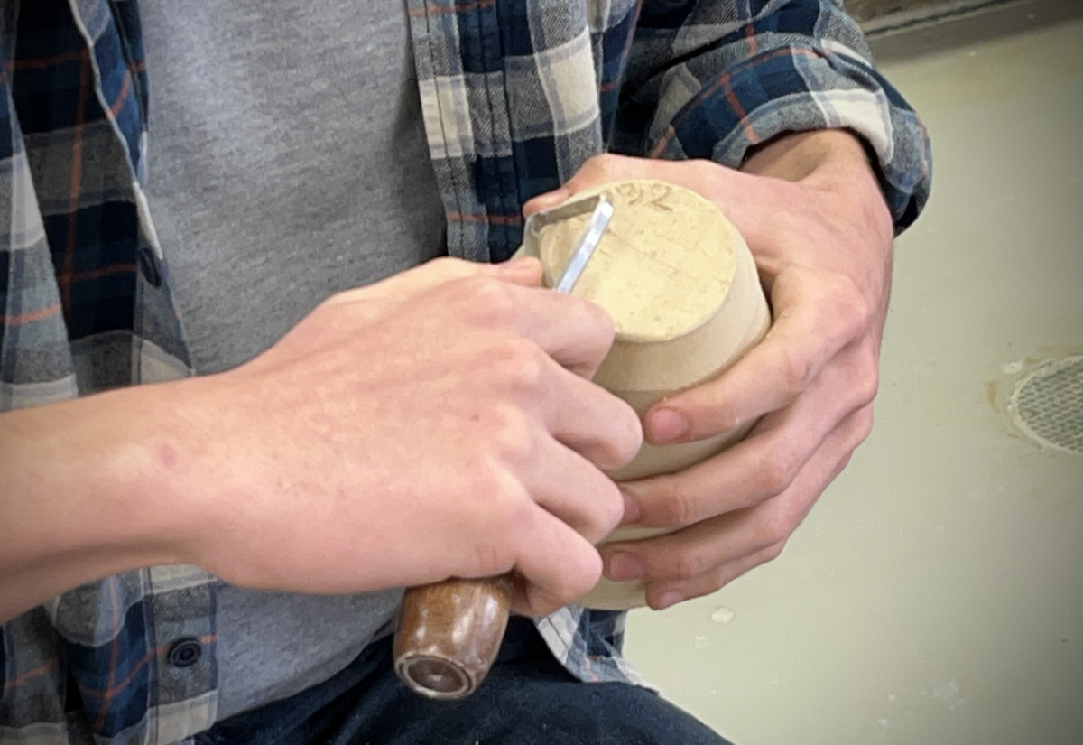 A students creates the bevel on the bottom of his cup.
