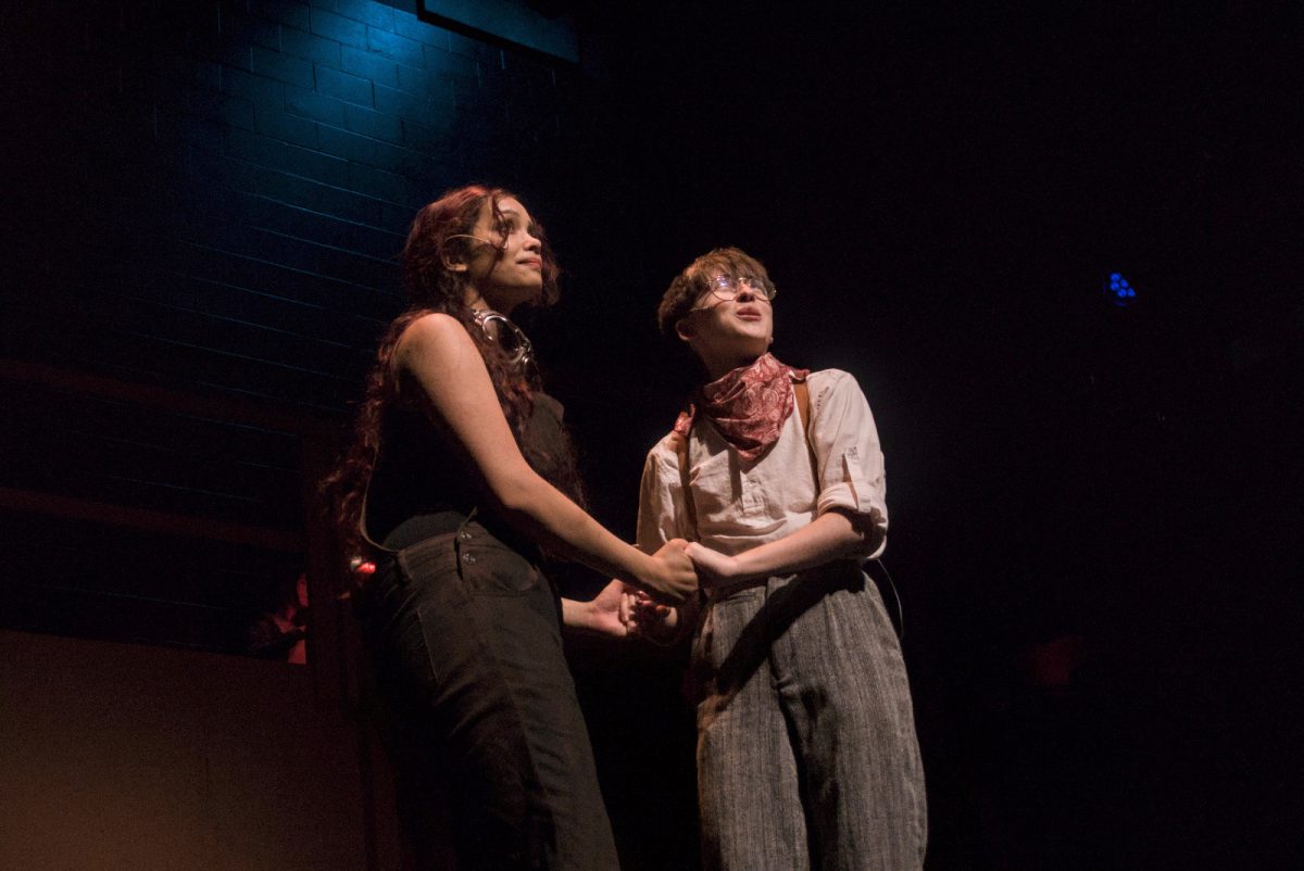 Eva Pudiyapura (Eurydice) and Grayson Rebello (Orpheus) look out into the audience as music swells in the background.