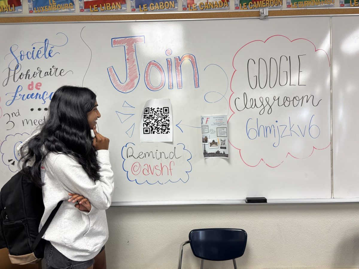 Nithya Mukkamala ('27) decides whether or not to participate while looking at the French Peer Tutoring poster