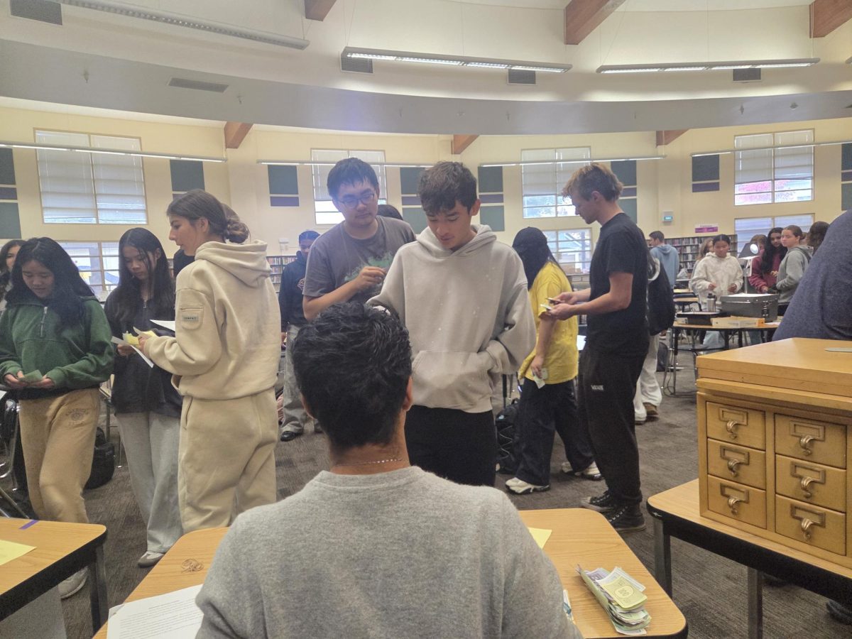 US History students participate in the stock market game taking place in the library. 