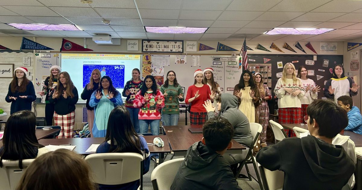 ASL carolers deck out in festive fits as they perform for Mrs. Heller's class, signing the word for "snow".
