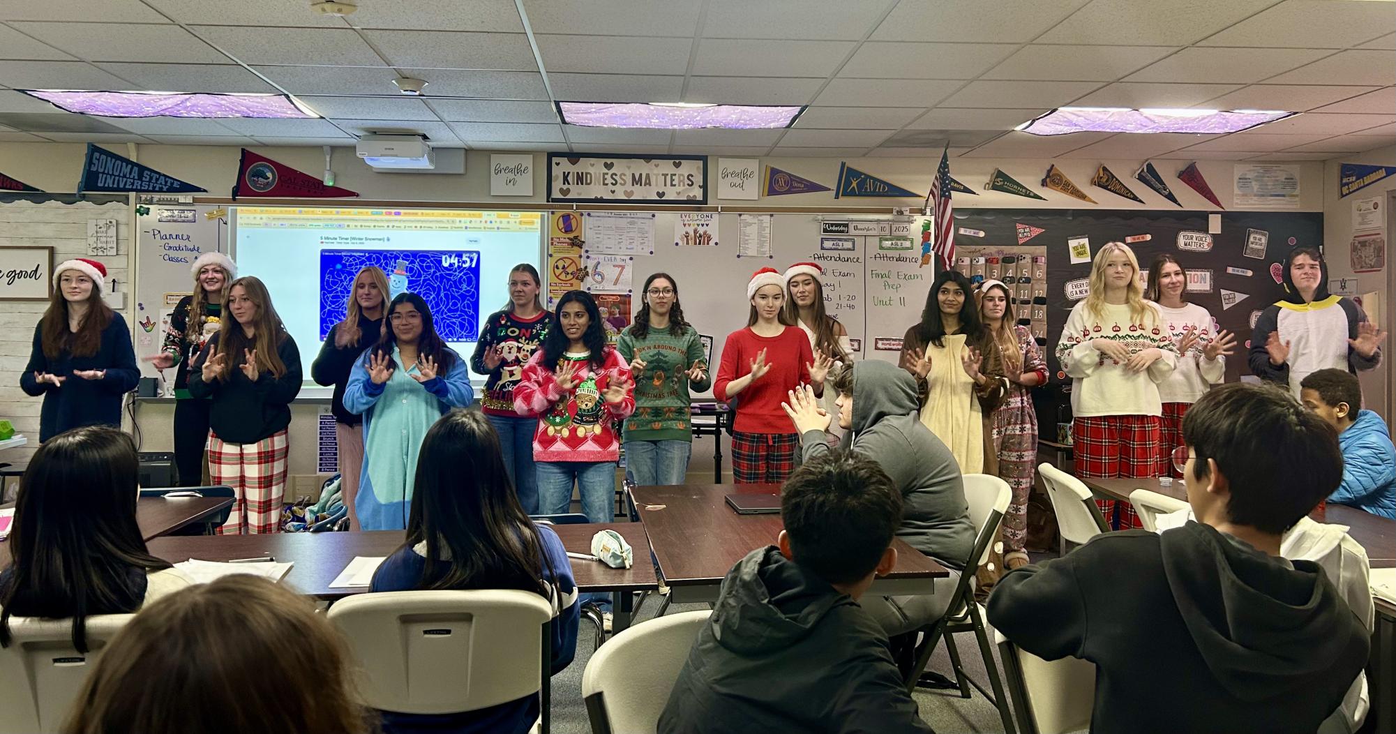 ASL carolers deck out in festive fits as they perform for Mrs. Heller's class, signing the word for "snow".