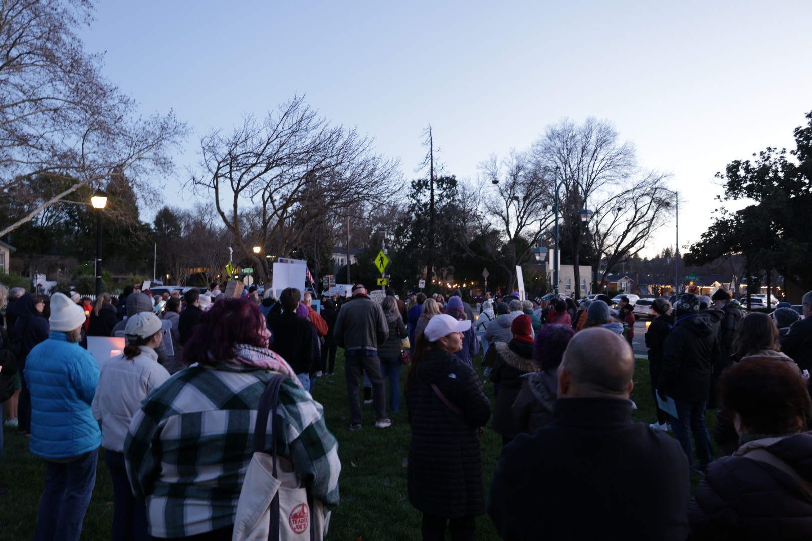 From young graduates to seasoned activists, a large crowd amasses at Delucci Park as the day grows dark to mourn the loss of Renee Good.