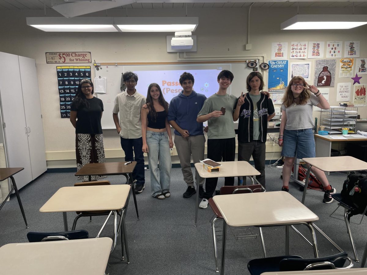 Members and officers of the Jewish Student Union posing in front of a slideshow teaching about and celebrating the Jewish holiday of Passover.