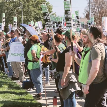 DUSD teachers, armed with signs, protest at the edge of a school. 
